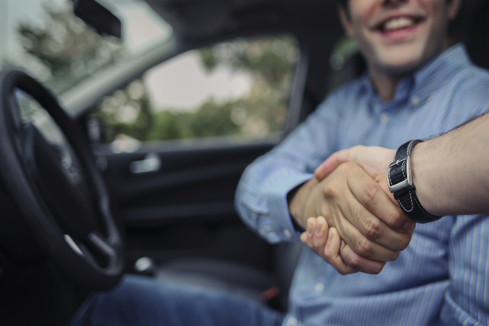 man in driver's seat shaking a hand