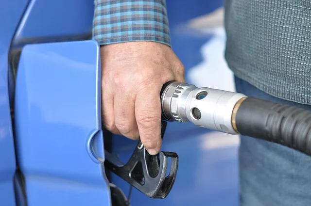 man pumping gas at blue car