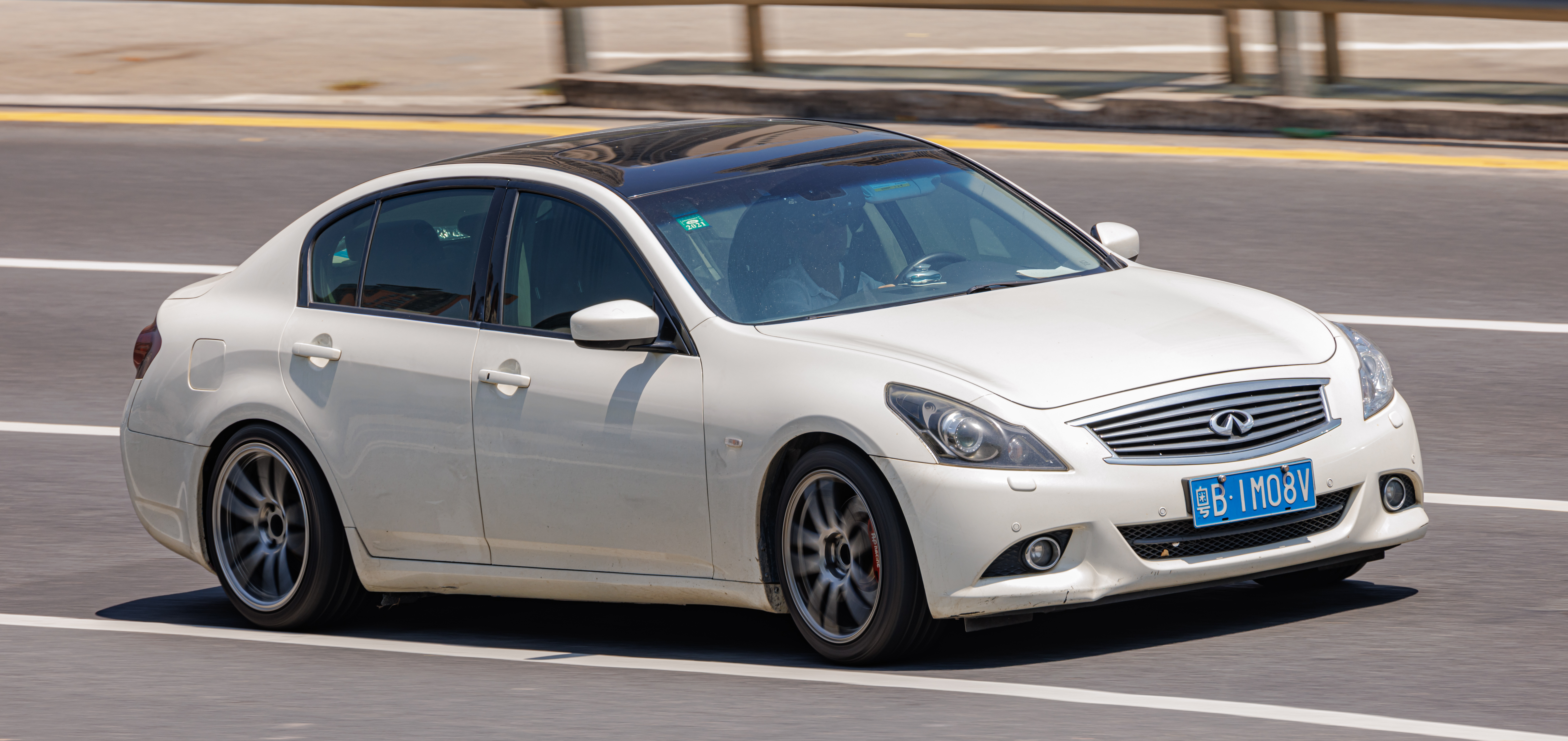 White Infiniti Q40 driving on a road