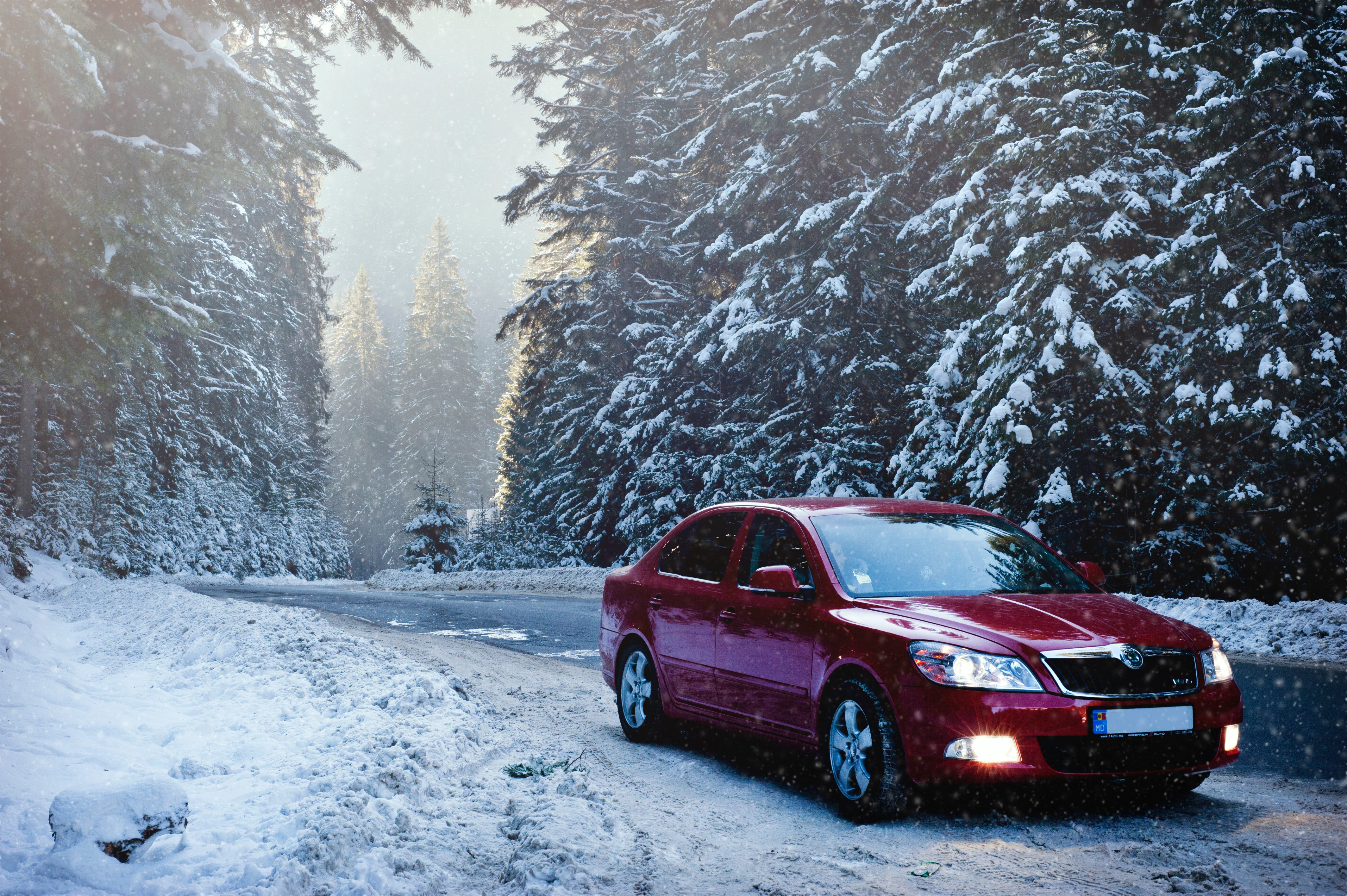 Red sedan driving down snowy road