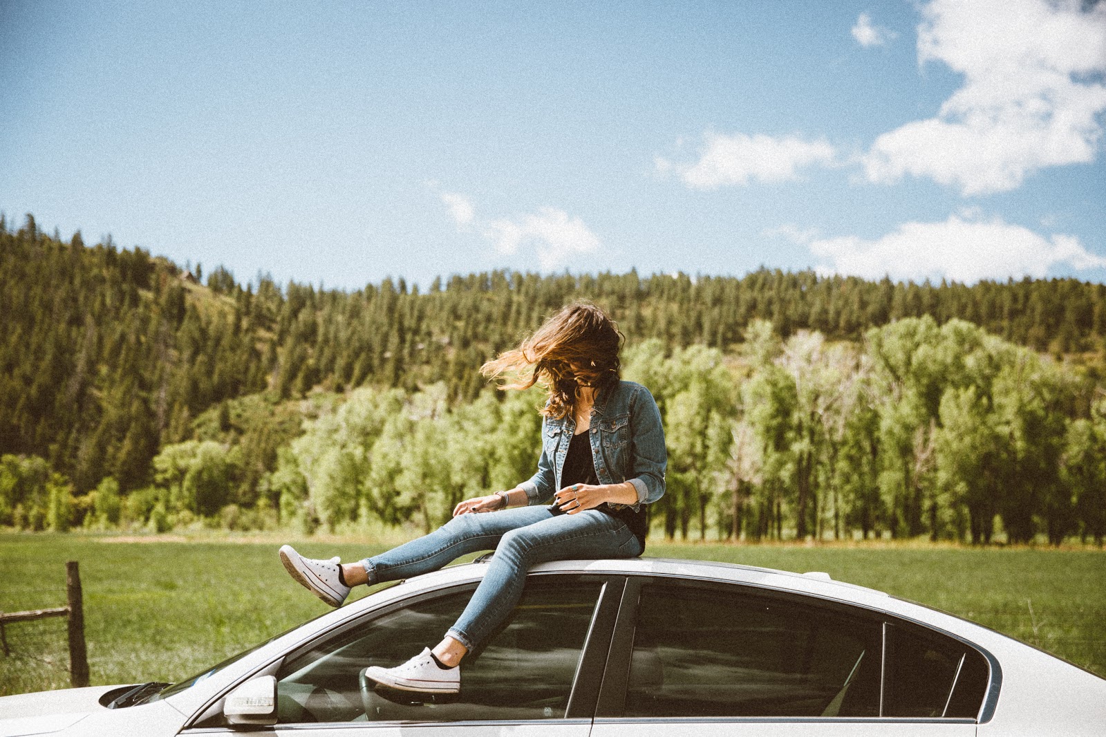 Photo of young woman sitting on top of car